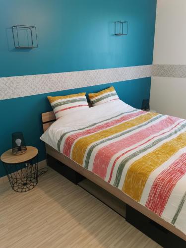 une chambre avec un lit et un mur bleu dans l'établissement Maison de la Solinoise, à Sainte-Soulle