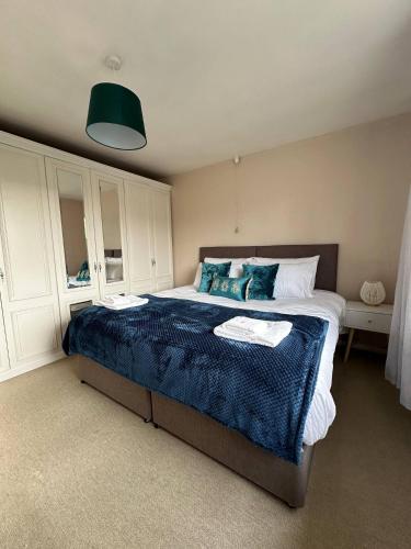 a bedroom with a large bed with a blue blanket at 3 Br House - Private Parking - Pool Table in Balderton