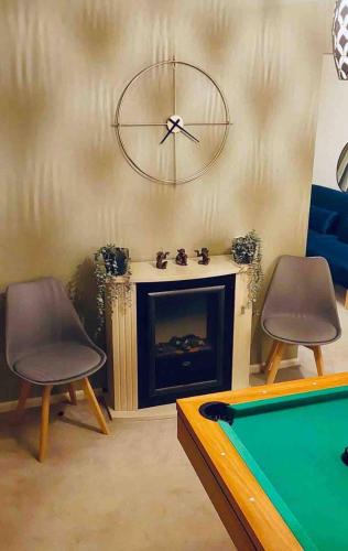 a living room with a pool table and a clock above a fireplace at 3 Br House - Private Parking - Pool Table in Balderton