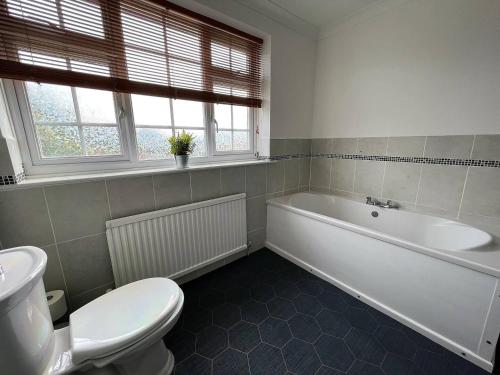 a bathroom with a white tub and a toilet at Spacious 5-bed - Perfect For Contractors 