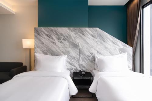 two beds sitting next to each other in a room at Thaya Hotel Bangkok in Bangkok