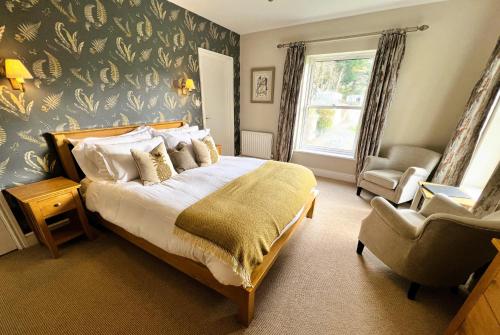 a bedroom with a large bed and a chair at Ravenstone Lodge Country House Hotel in Keswick