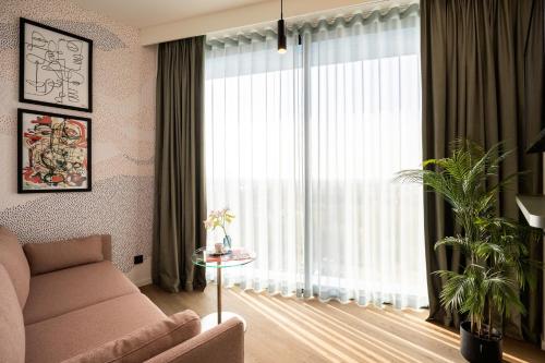 a living room with a couch and a large window at voco Brussels City North by IHG in Vilvoorde