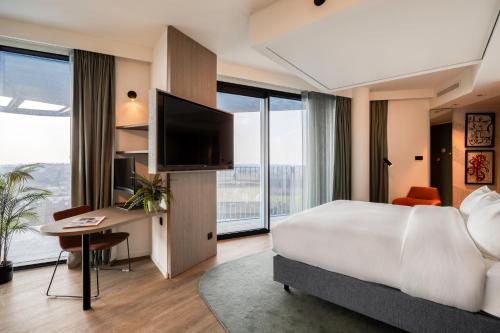 a hotel room with a bed and a desk and a television at voco Brussels City North by IHG in Vilvoorde