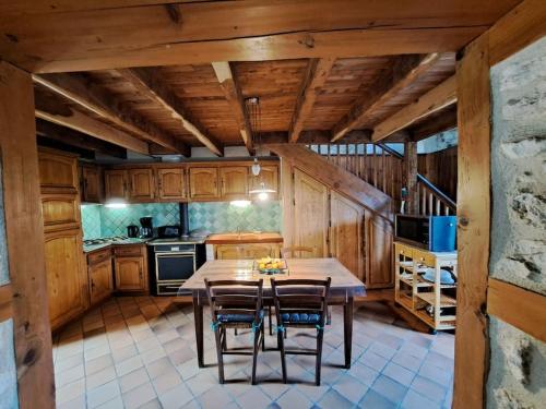 une cuisine avec des armoires en bois et une table et des chaises dans l'établissement Périgord Vert - Animaux acceptés, à Quinsac