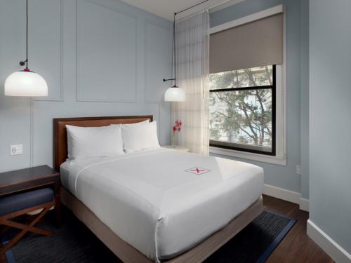 a bedroom with a large white bed and a window at Axiom Hotel in San Francisco