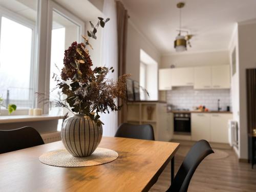 a vase with flowers on a wooden table in a kitchen at AL Apartment, Central & Cozy in Panevėžys