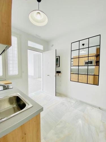 una cucina bianca con lavandino e specchio di SOLEO suite a Jerez de la Frontera