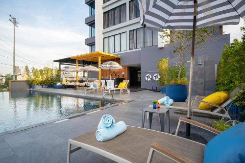 a pool with tables and chairs next to a building at Thaya Hotel Bangkok in Bangkok