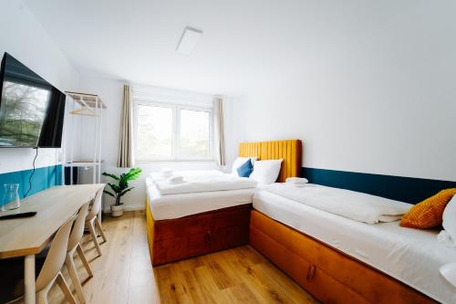 a room with two beds and a desk and a table at Jenapartments for7 Boxspring & Smart TV & Waschmaschine in Jena