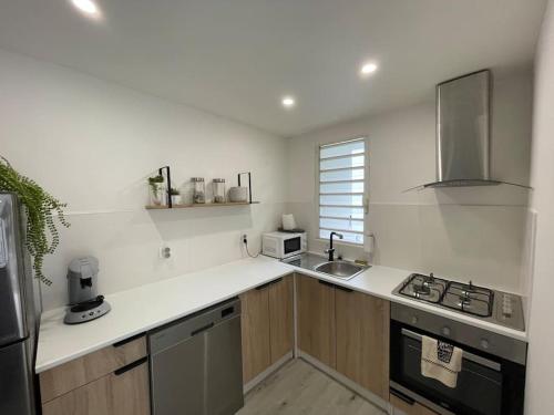 a white kitchen with a sink and a stove at Le Ravenala Maison SPA 2 chambres 2 salles de bain in Saint-Denis