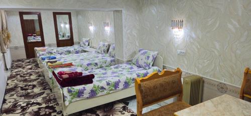 Zimmer mit 2 Betten, einem Tisch und Stühlen in der Unterkunft HOTEL-129 in Samarkand