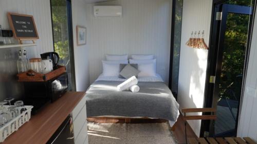 een slaapkamer met een bed, een tafel en een raam bij The Kauri Retreat 1 in Waitoki