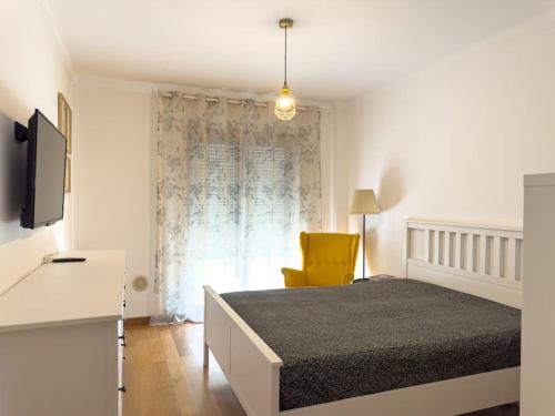 um quarto com uma cama e uma cadeira amarela em apartamento grande da Gama em Lisboa