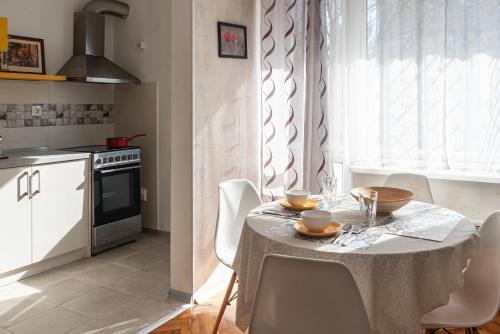 a kitchen with a table with white chairs and a kitchen with a window at Photo Art apartment in Burgas City