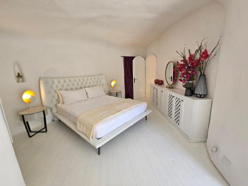 Maridea - La Caletta - Luxury Villa في بونسا: غرفة نوم بيضاء مع سرير وزهور في الغرفة