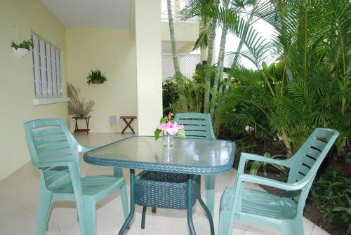 un tavolo blu e delle sedie con un vaso di fiori sopra di 26 Margate Gardens a Bridgetown