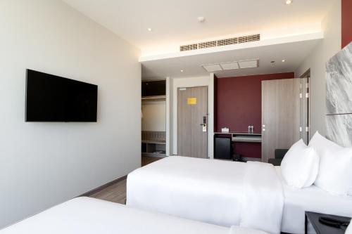 a hotel room with a bed and a flat screen tv at Thaya Hotel Bangkok in Bangkok