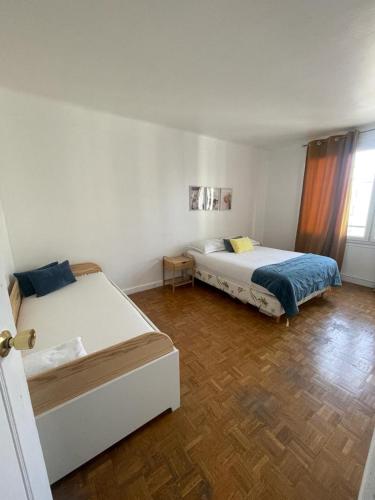 una camera con 2 letti e un pavimento in legno di magnifique appartement a Parigi