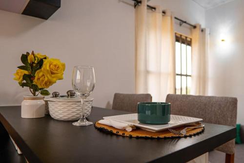 a table with a green cup and a wine glass at Le Nid des Lys in Lomé
