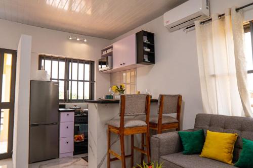 a kitchen with a refrigerator and a table and chairs at Le Nid des Lys in Lomé