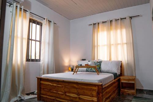 um quarto com uma cama com uma moldura de madeira e janelas em Le Nid des Lys em Lomé