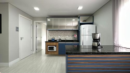 a kitchen with a black counter top and a refrigerator at 08- Studio perfeito para família! Aconchegante e novo! in Curitiba