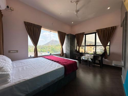a bedroom with a bed and a desk and windows at OM LINGESWARAN HOME STAY Tiruvannamalai in Tiruvannāmalai