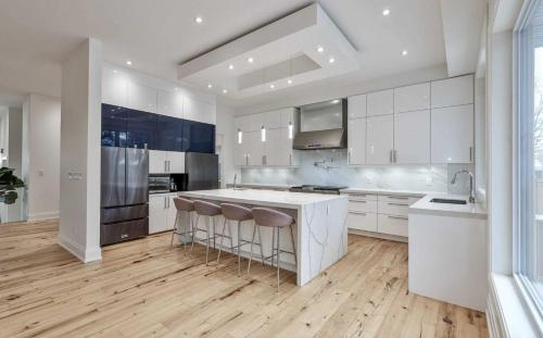 a large kitchen with white cabinets and a wooden floor at Executive Room in Toronto next to Yorkdale shopping centre in Toronto