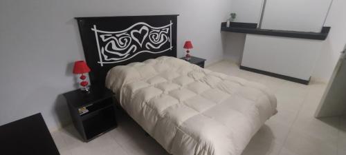 a bedroom with a white bed with a black and white headboard at CASACLUBGOLF in Santiago del Estero