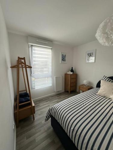 - une chambre avec un lit rayé et du parquet dans l'établissement Appartement Plein Centre, à Saint-Brévin-les-Pins