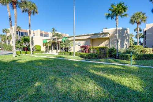 a house with palm trees in front of a yard at Comfortable Jensen Beach Condo with Pool View! in Jensen Beach