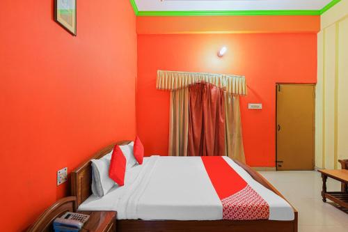 Bett in einem Zimmer mit orangefarbener Wand in der Unterkunft OYO Flagship 86687 Hotel Anandlok in Haldwani-Kathgodam