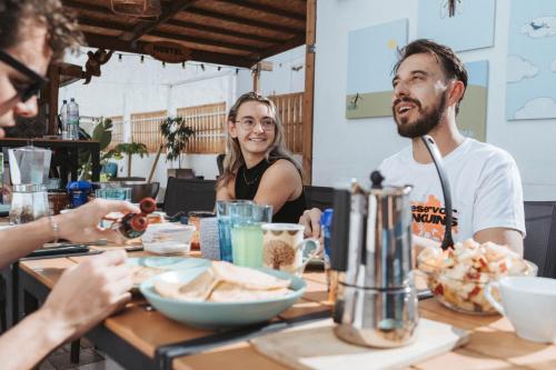 grupa ludzi siedzących przy stole jedzących jedzenie w obiekcie La Ventana Azul Surf Hostel w mieście Las Palmas de Gran Canaria