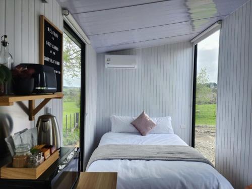 1 dormitorio con cama y ventana grande en Dairy Flat Farm Cabin 1, en Waitoki