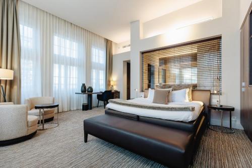 a bedroom with a king sized bed and a chair at Terhills Hotel in Maasmechelen