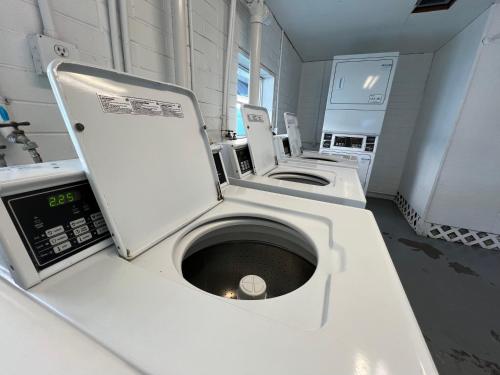 La salle de bains blanche est pourvue d'un lave-linge et d'un lavabo. dans l'établissement Flamingo Tiny Home, à Sarasota