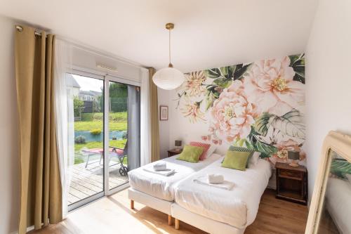 een slaapkamer met een muurschildering van bloemen op de muur bij La perle de mer - Charmante maison avec jacuzzi in Erquy