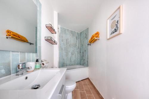 Baño blanco con lavabo y aseo en Appartement cosy et calme, en Élancourt