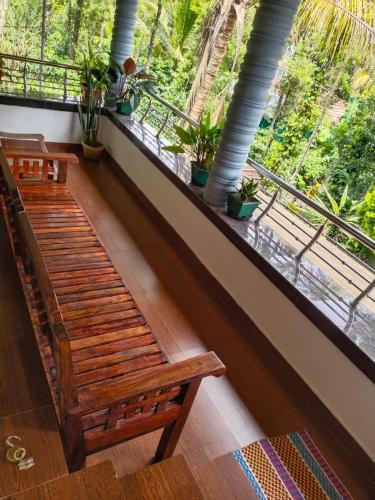2 drewniane ławki w pokoju z dużym oknem w obiekcie Mary's homestay w mieście Kalpatta