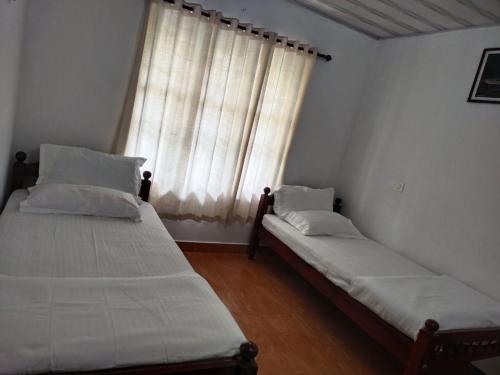 dwa łóżka w pokoju z oknem w obiekcie Mary's homestay w mieście Kalpatta