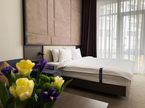 a bedroom with a bed and a vase of flowers at Ribas Rooms Odesa in Odesa