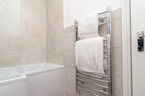 a bathroom with a towel rack next to a bath tub at Little Boat: A Modern Beachside Flat in Bournemouth