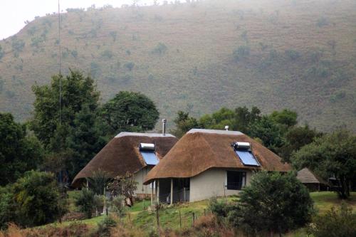 an old house with a thatched roof in a field at Sungubala Eco Camp in Bergville