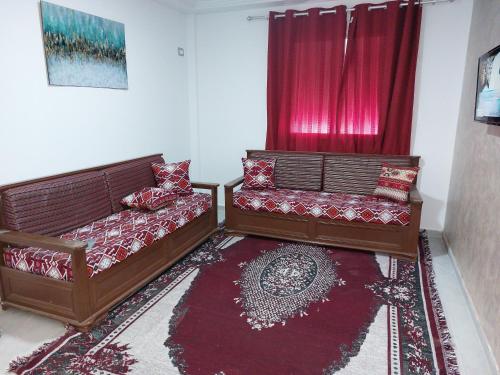 sala de estar con 2 camas y cortina roja en Dar Zaineb, en Túnez