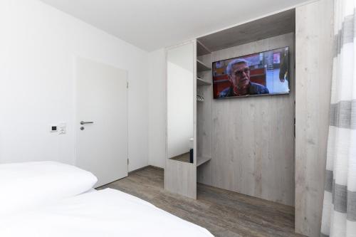 a room with a tv on a wall with a bed at Haus Strandkorb mit Frühstücksoption in Bensersiel
