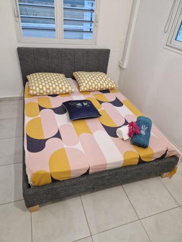 uma cama com um edredão colorido e almofadas em An'Kanna em Petit-Bourg