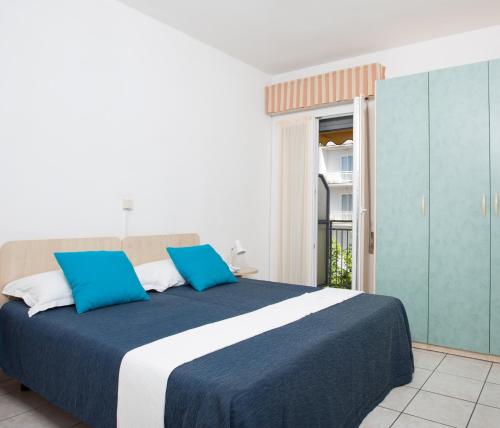 1 dormitorio con 1 cama grande con almohadas azules en Hotel Esedra, en Milano Marittima