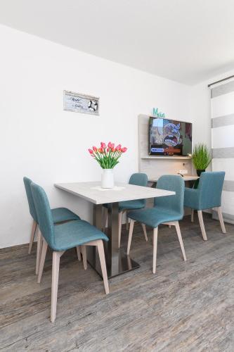 a dining room with a white table and blue chairs at Haus Strandkorb mit Frühstücksoption in Bensersiel