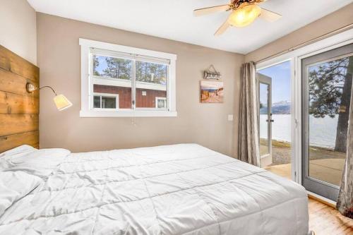 a bedroom with a white bed and a window at Secluded Cabin On The Lake #7 in West Kelowna